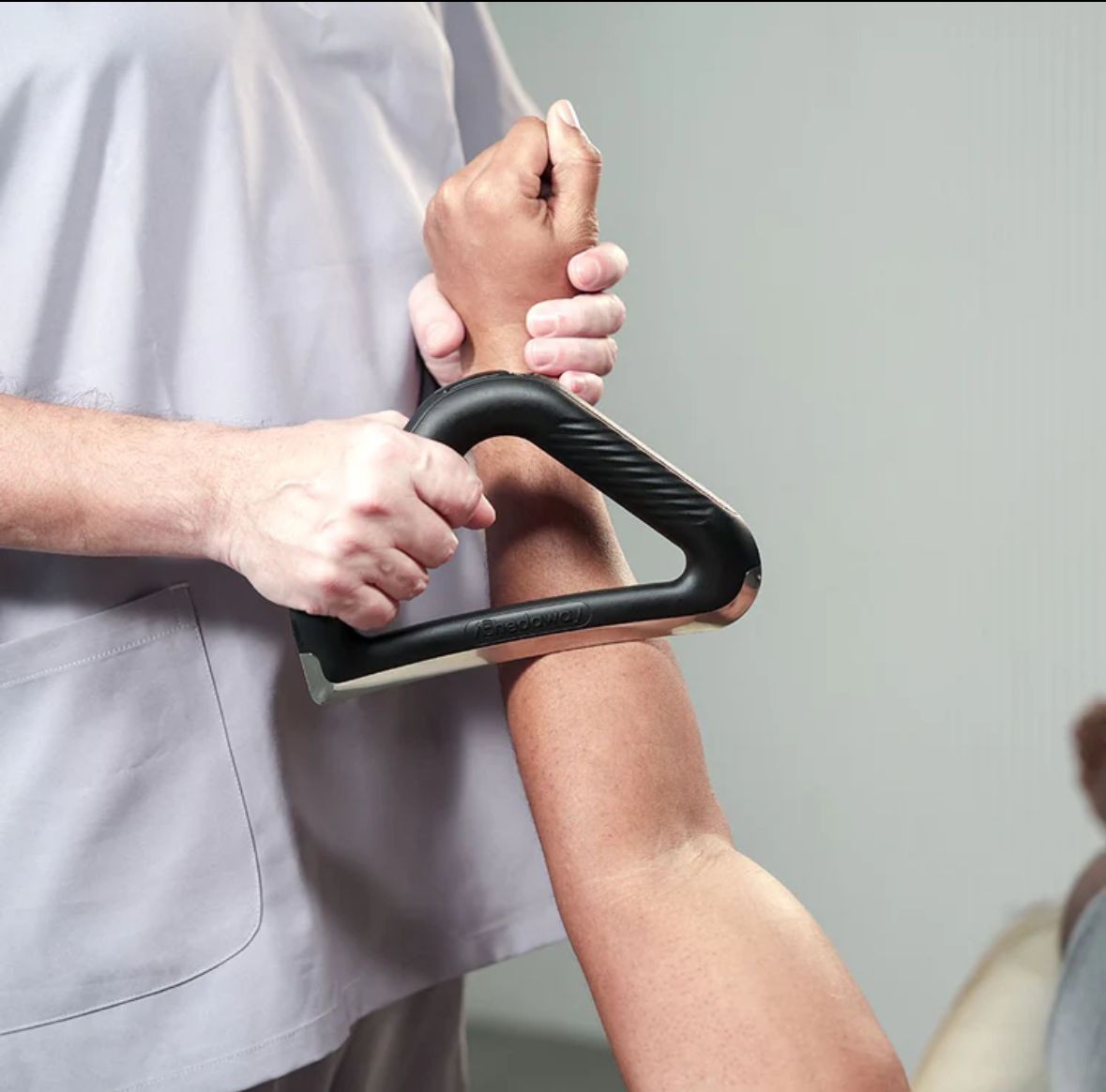 Therapist using a massage tool on a person's arm.